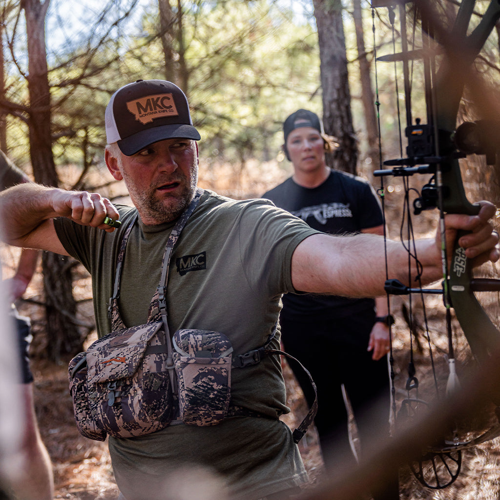 Josh Smith of Montana Knife Company holds a bow at an archery event. 