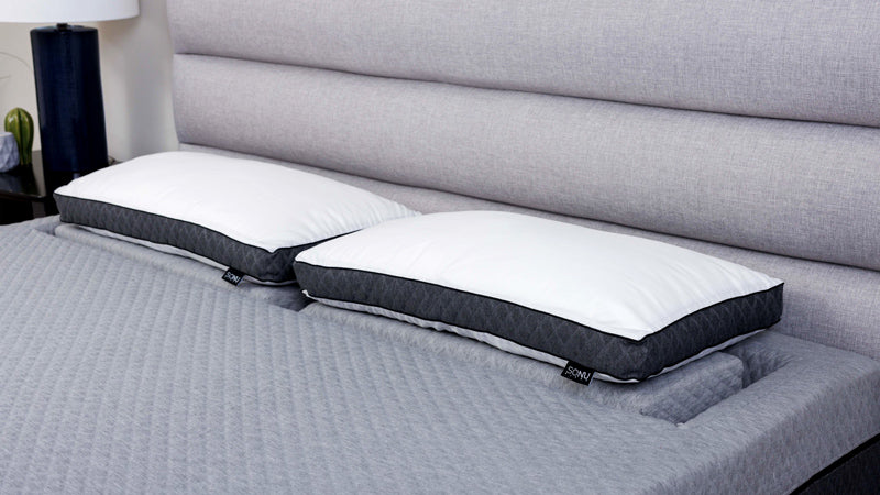 Two SONU Top Pillow Deluxes in white and dark grey sitting on top of the Support Pillows in the Comfort Channel of the SONU mattress