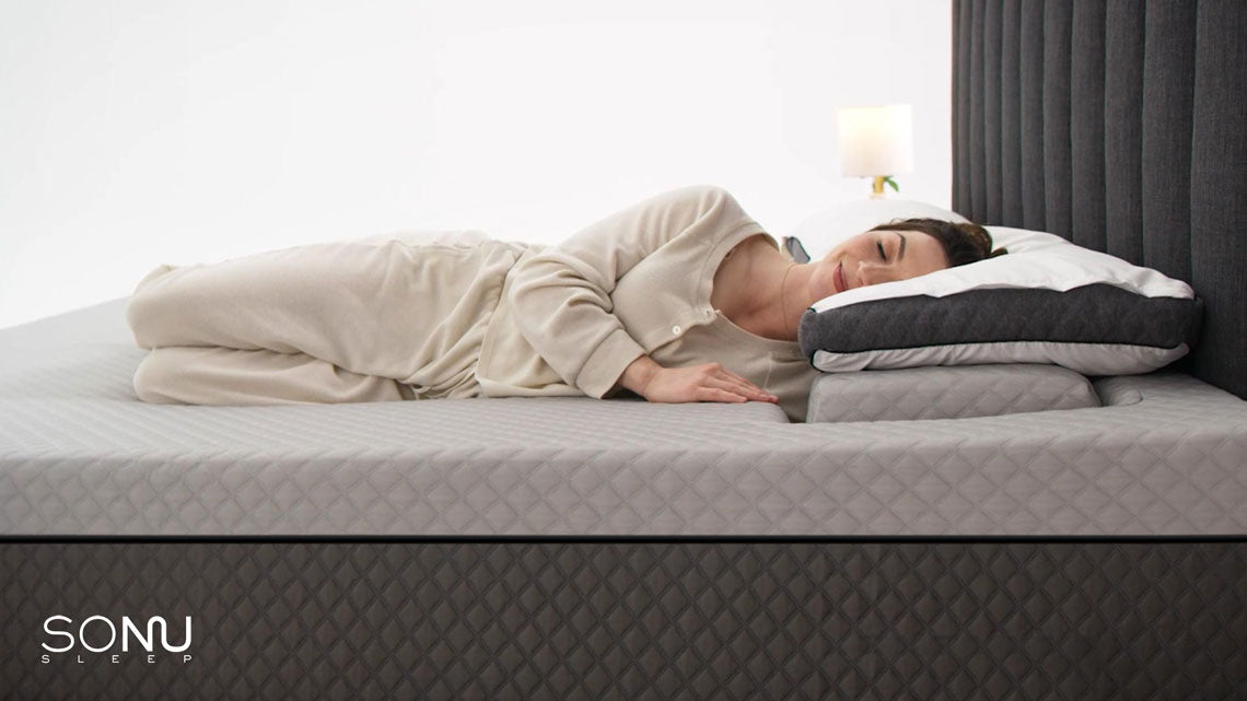 A photo of a female comfortably sleeping in a Sonu mattress on dark grey bed frame.