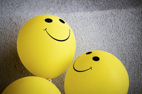 yellow balloons with smiley faces on them on a wall