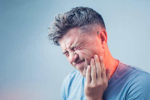 Man in pain with his hand on his cheek indicating a toothache