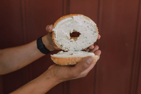 two hands holding a seeded bagel