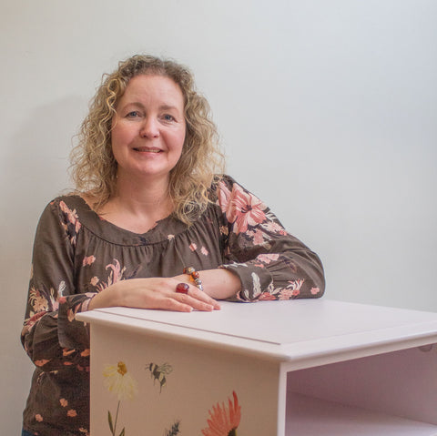 An image of Michelle from Shel's Shabby Chic smiling, standing with a perfectly pink, hand painted bedside table
