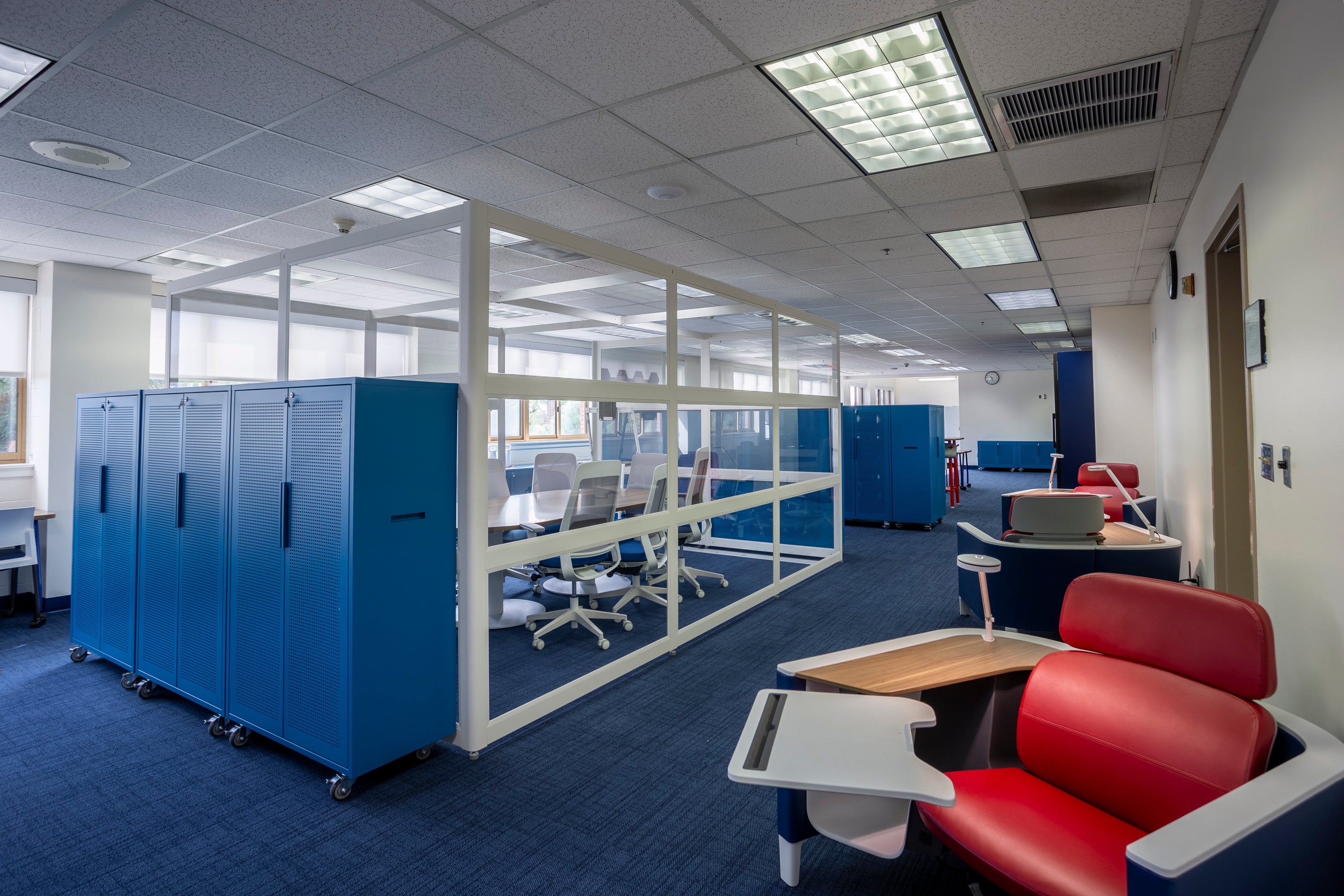 Teacher workroom image with tall storage cabinets, a small glassed in conference room, and flexible seating.