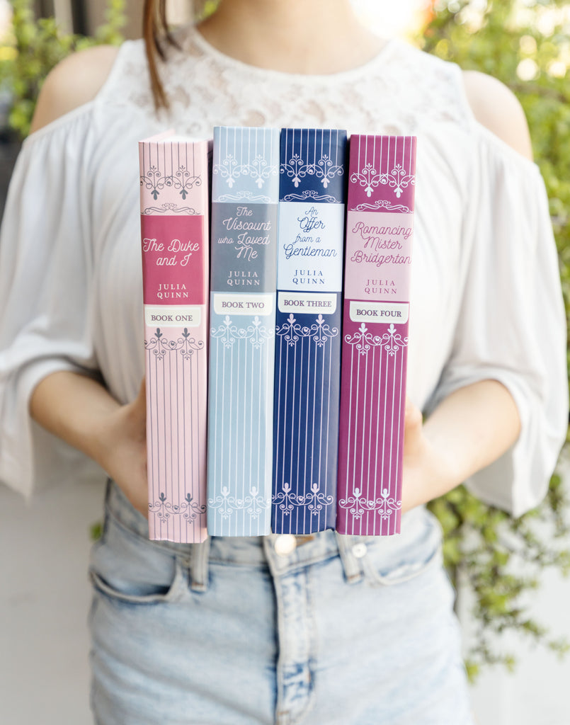 A girl holding 4 books of The Bridgerton Collection from Once Upon a Book Club 