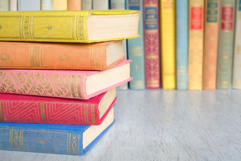 Stack of colorful vintage books, reminiscent of Once Upon a Book Club's celebration of timeless literary joy.