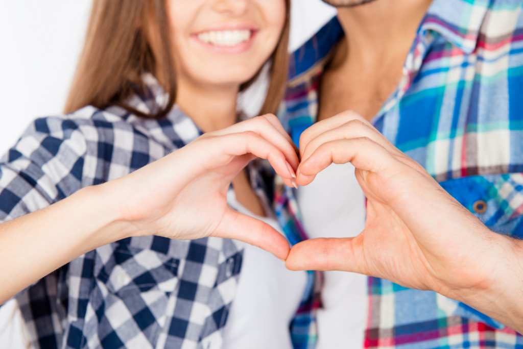 Two people forming a heart shape with their hands, focused on the hands.
