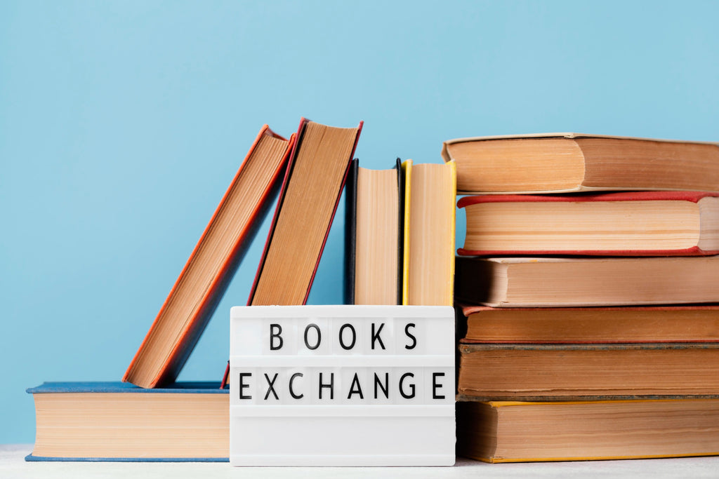 Stacks of books on either side of a sign that reads 'Books Exchange' against a blue background.