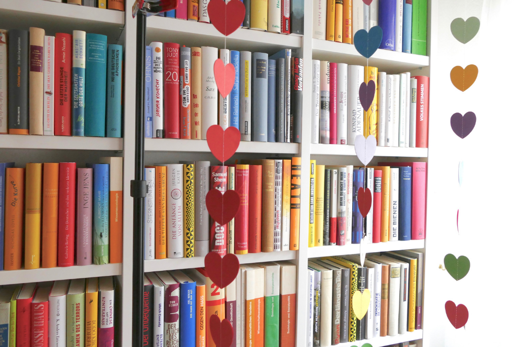 Bookshelf adorned with hanging heart decorations in various colors.