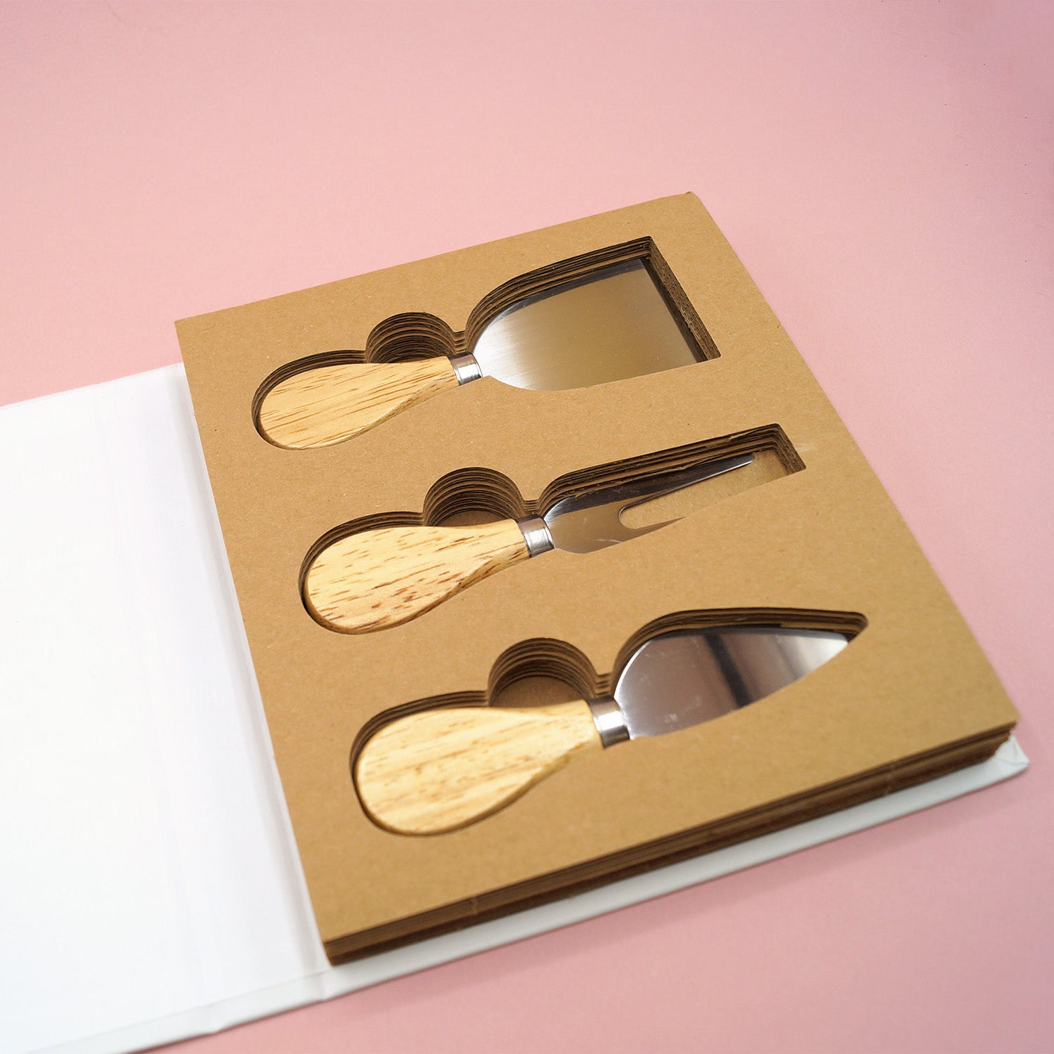 An open box shows a 3 piece cheese knife set including a flat blade knife, cheese fork, and spade knife. All have wooden handles.