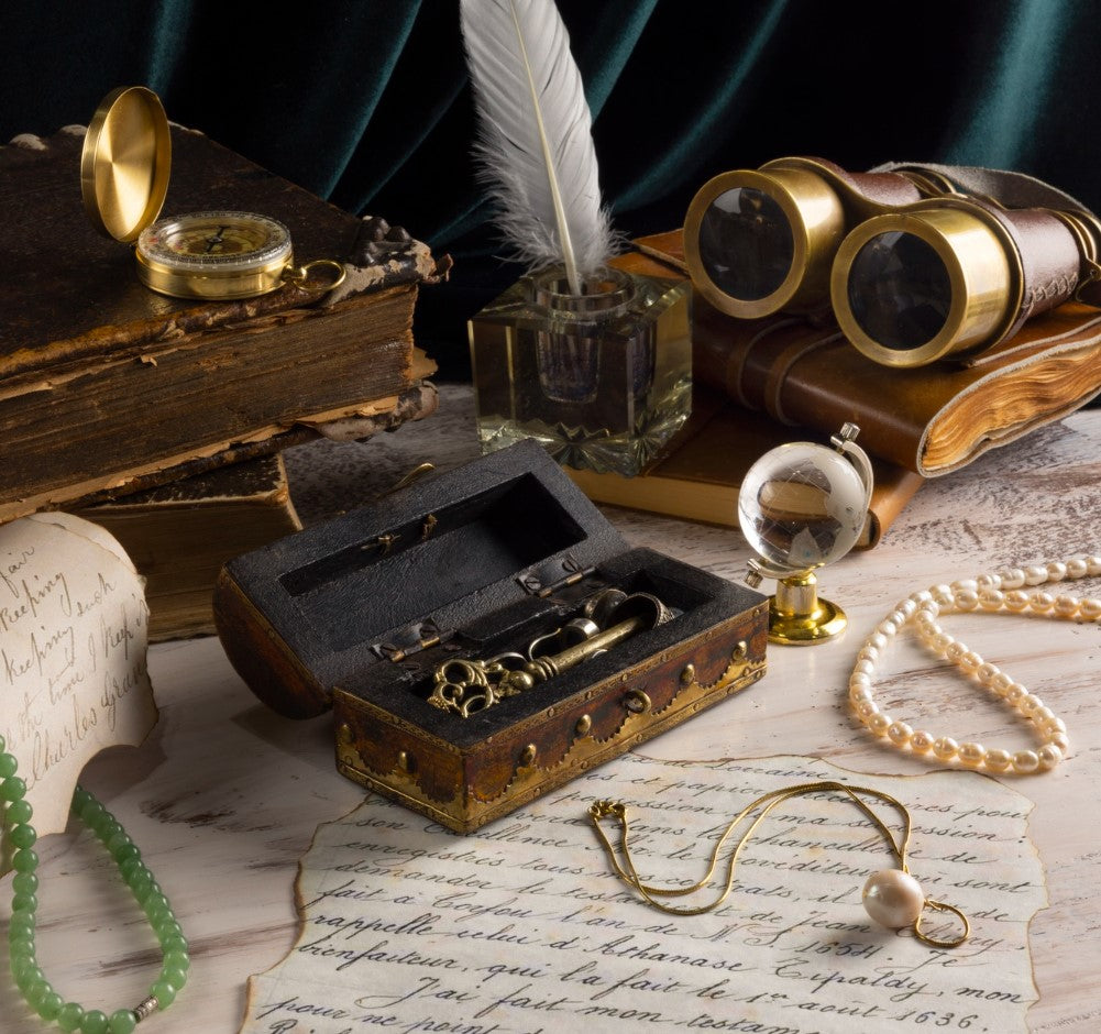 Vintage exploration and writing accessories, including books, a compass, binoculars, and a feather quill.