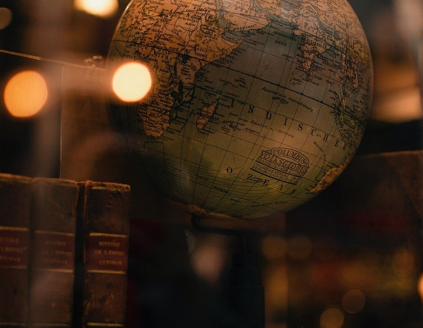 A vintage globe illuminated by soft light, with focus on the 'Indischer Ozean' (Indian Ocean), surrounded by blurred antique books in a cozy, warm setting, evoking a sense of exploration and history.