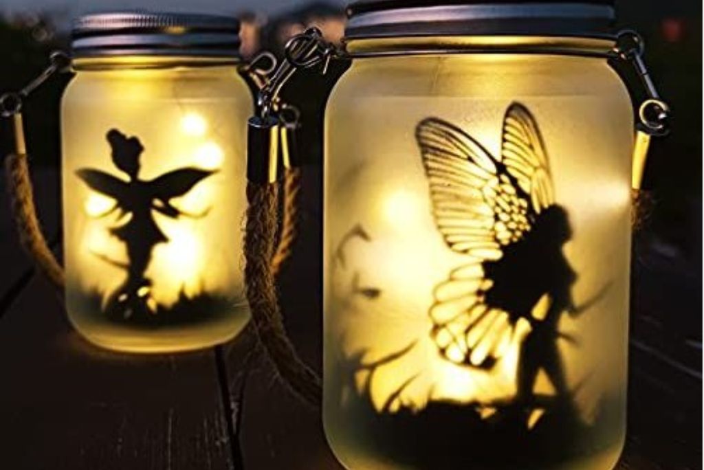 Mason jar lanterns with fairy silhouettes creating a magical glow in the twilight.