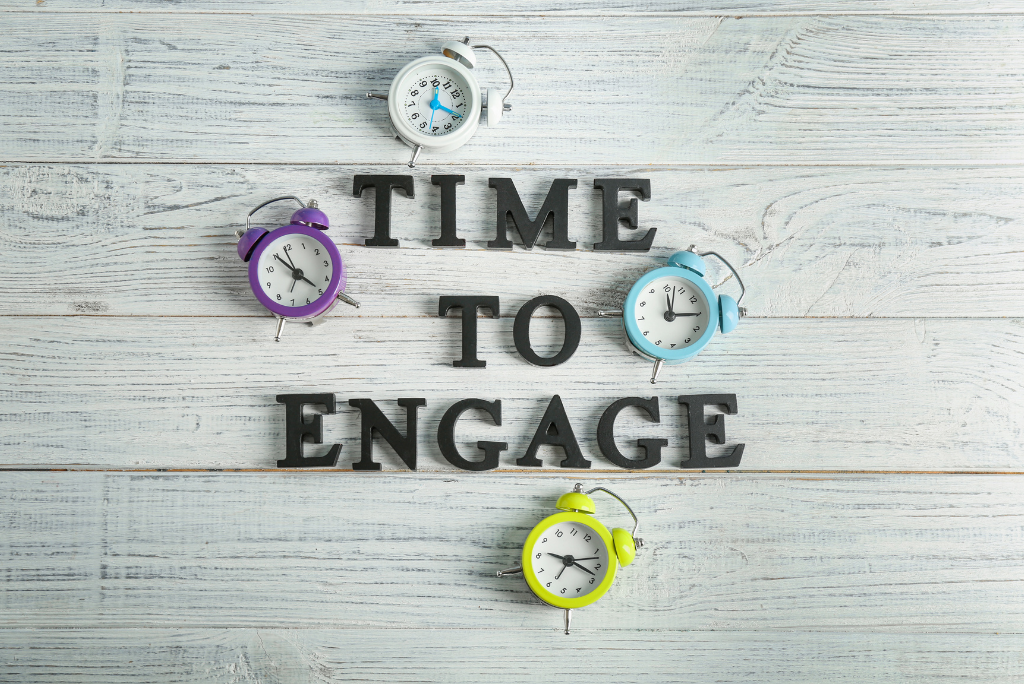 Alarm clocks and 'TIME TO ENGAGE' letters on wooden background.