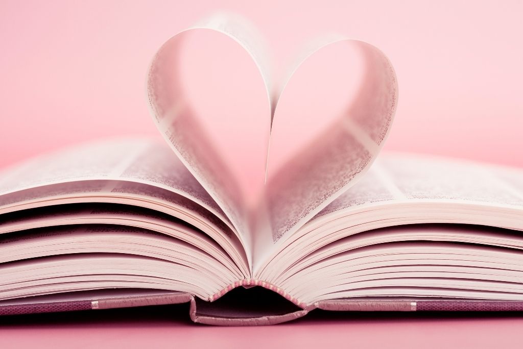Open book with pages folded into a heart shape on a pink background, symbolizing Once Upon a Book Club's love for literature.
