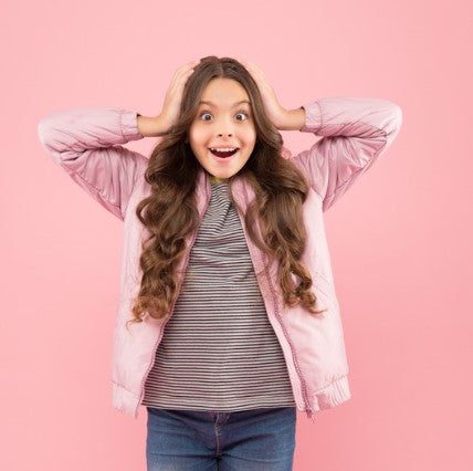 A middle-grade girl with both her hands on the sides of her forehead and a silly face.