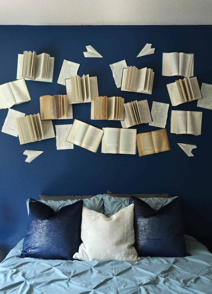 A lot of books opened on the wall behindthe bed with flattering pages.