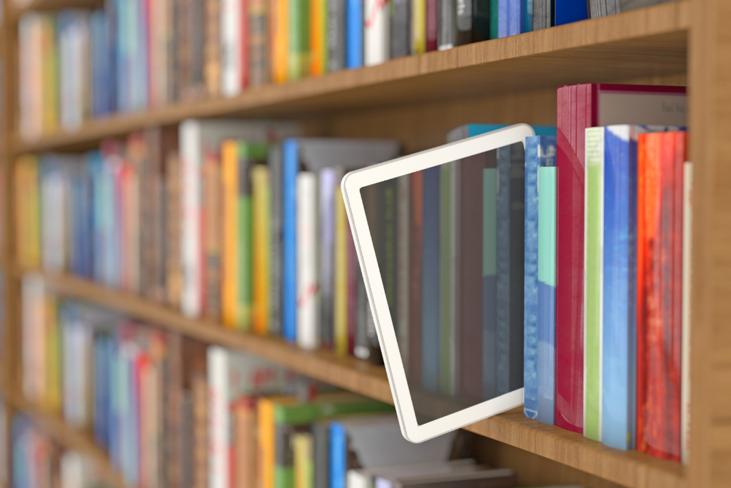 A tablet leaning against books on a wooden shelf.