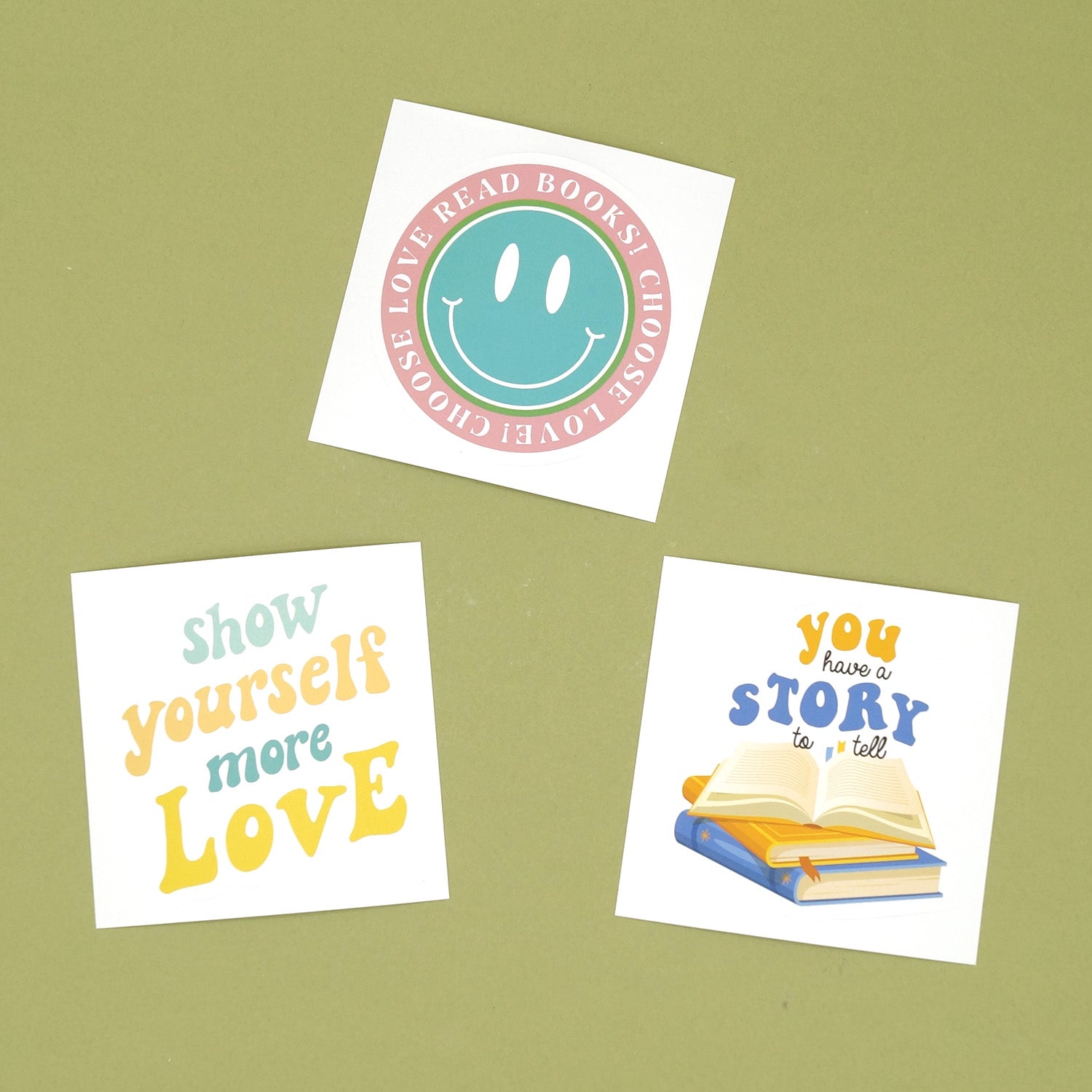 Three stickers are on a green background. The top one says Choose Love Read Books! Choose Love. The left one says Show Yourself More Love. The right one says You Have a Story to Tell.