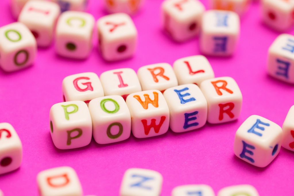 Beads spelling 'GIRL POWER' on a vibrant pink background.
