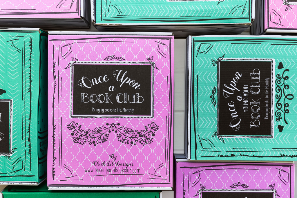 Close-up of OUABC book club boxes with vibrant pink and teal covers.