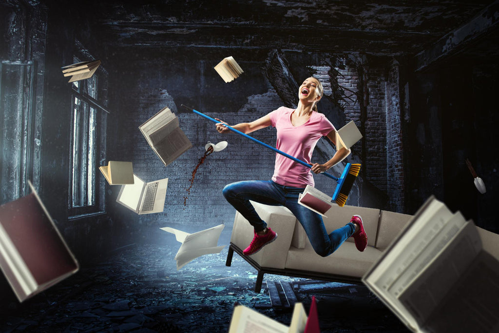 Joyful woman with headphones rides a sofa mid-air, surrounded by flying books in a dark room.