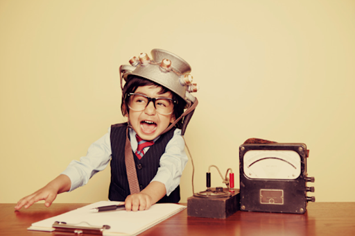 Excited young boy with a quirky helmet sits by vintage equipment, playing a time-traveling detective.