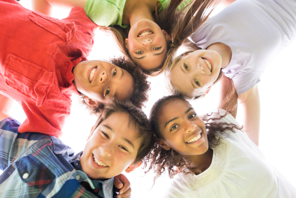 A group of joyful diverse children looking down into the camera.