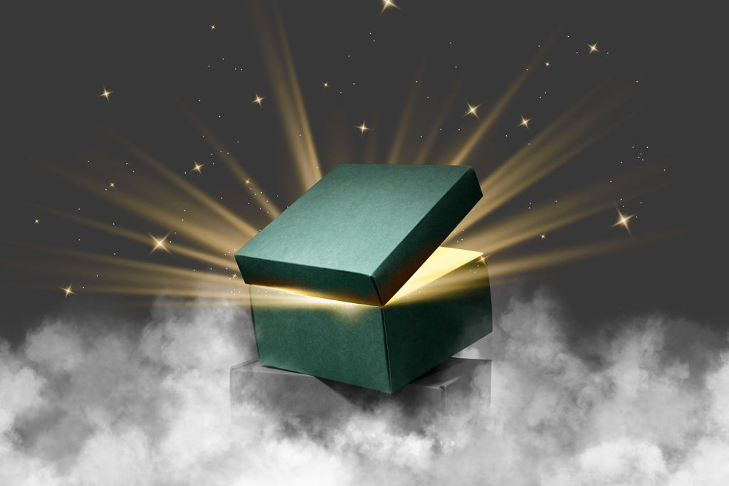 Mystical green gift box opening with magical golden light and stars on a cloudy backdrop.