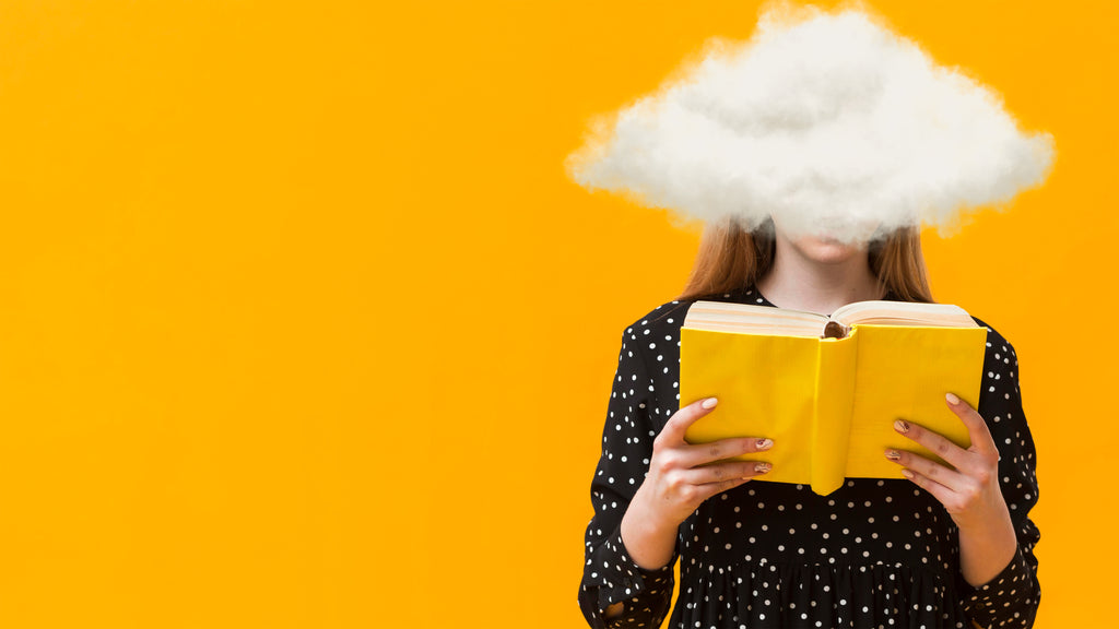 A creative concept with a woman reading a yellow book, her head obscured by a fluffy white cloud against a vivid orange background, illustrating imagination taking flight through reading.