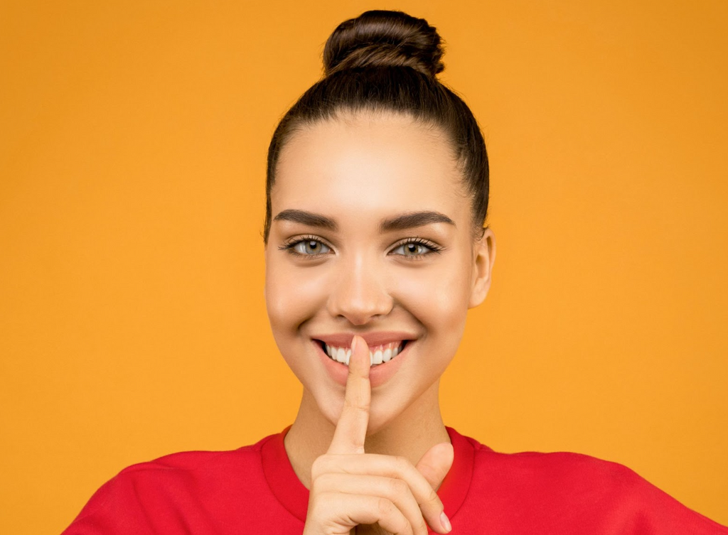 woman in red shirt with finger to mouth quite