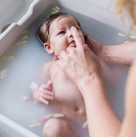 Mother poking baby's nose during bathtime