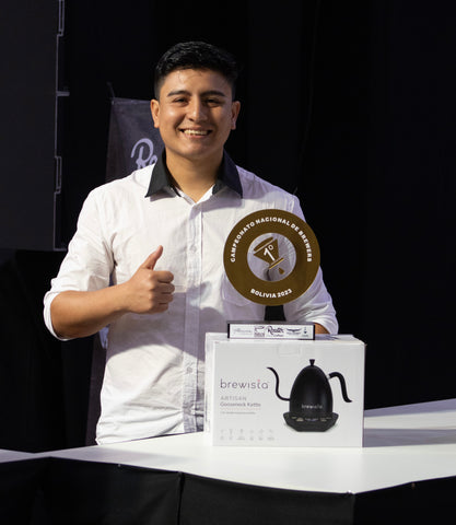 Quino poses with his Bolivia Brewers Cup trophy and a new Artisan Electric Gooseneck Kettle in Matte Black.