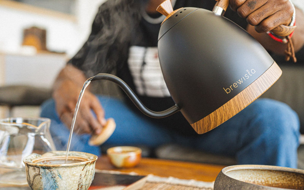 Taurean Nixon is pouring water from a Brewista Gooseneck Kettle in matte black into a teacup.