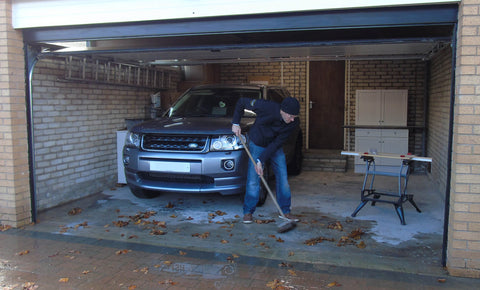 Man sweeping leaves and water out of a garage