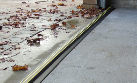 Garage with an installed garage door threshold seal stopping water and leaves