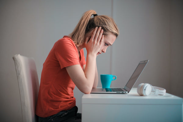 Fehér nő laptop előtt ül, stresszel a munkában.