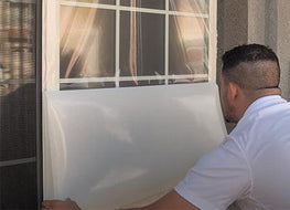 an installer is pulling the window film liner downwas to apply the product to the outside of the window