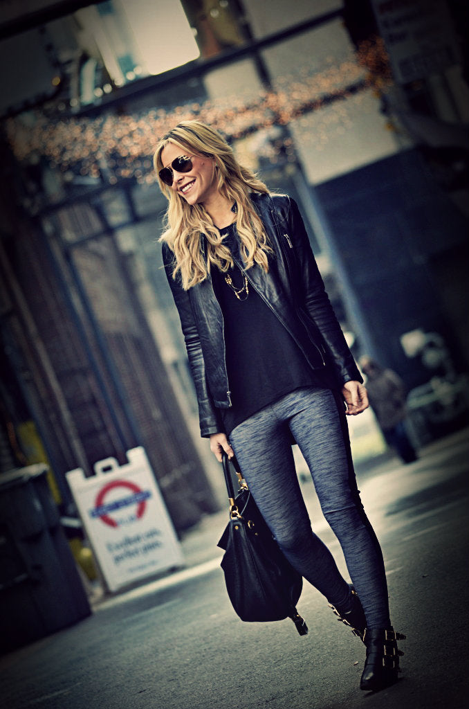 Woman in black leggings and leather jacket standing
