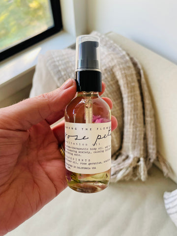 picture of a hand holding rose petal infused body oil