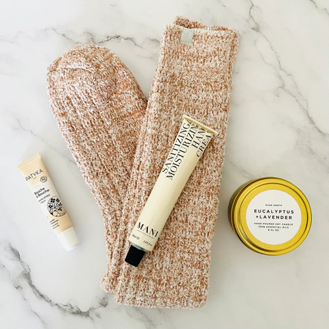 gift box featuring cozy socks, candle, hand moisturizer and lip balm