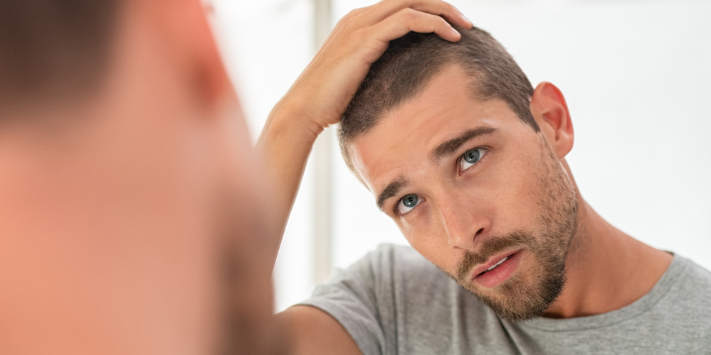 Man looks at his irritated scalp in the mirror