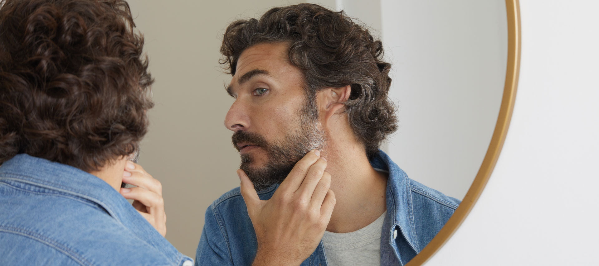 man inspecting his grey beard in mirror