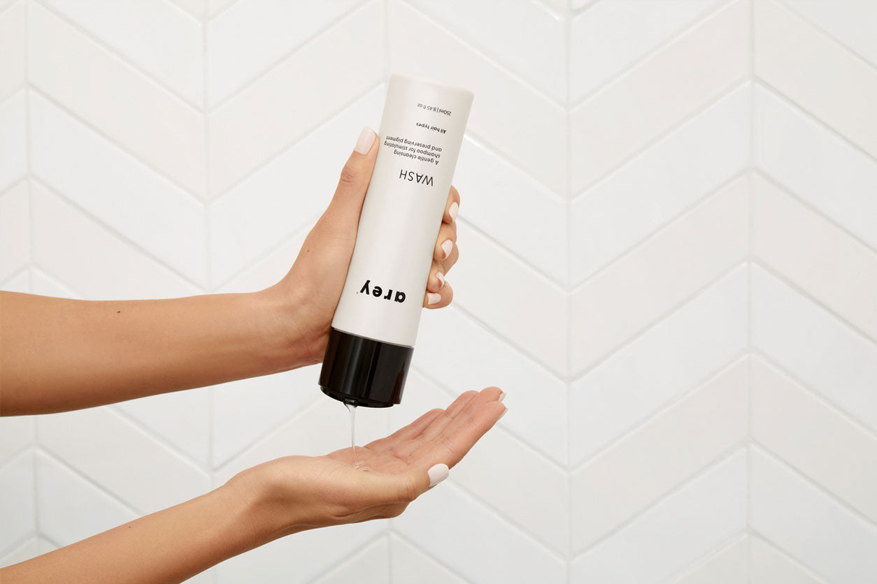 Woman in shower pours Arey Wash shampoo for grey hair into her hand