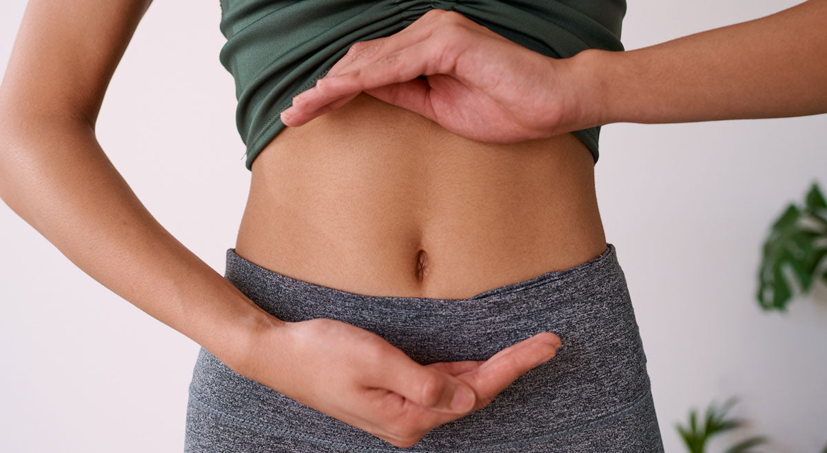 Woman with hands around her middle to indicate good gut health