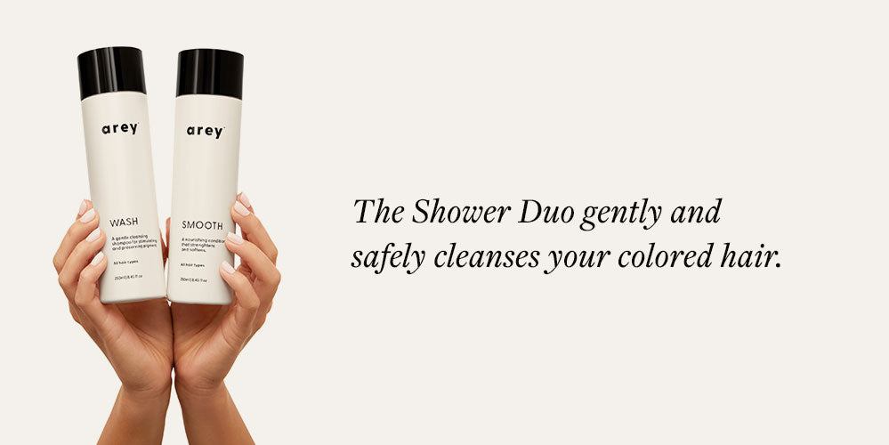 hands holding shampoo and conditioner bottles