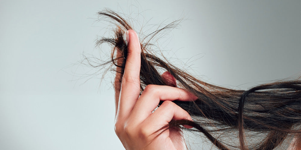 woman holding strands of damaged hair between her fingers