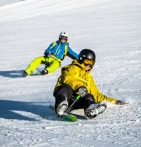 2 Personen fahren mit dem Schlitten Ski hinunter