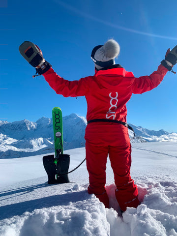 Personne de dos avec une luge Snooc plantée dans la neige devant le mont blanc