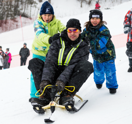 adulte sur une luge pour enfant avec les genoux proche du menton